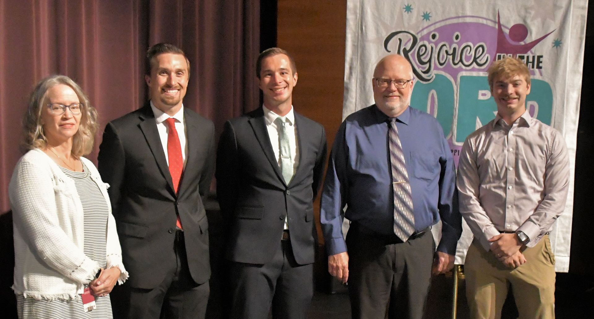 5 newly installed faculty smiling at the camera while on stage at FVL