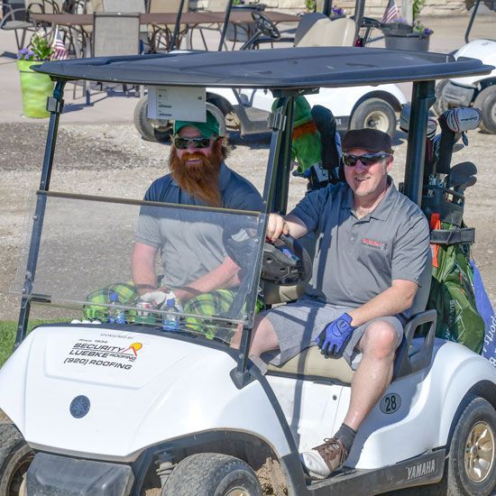 Two men in a golf cart, heading out toward the course