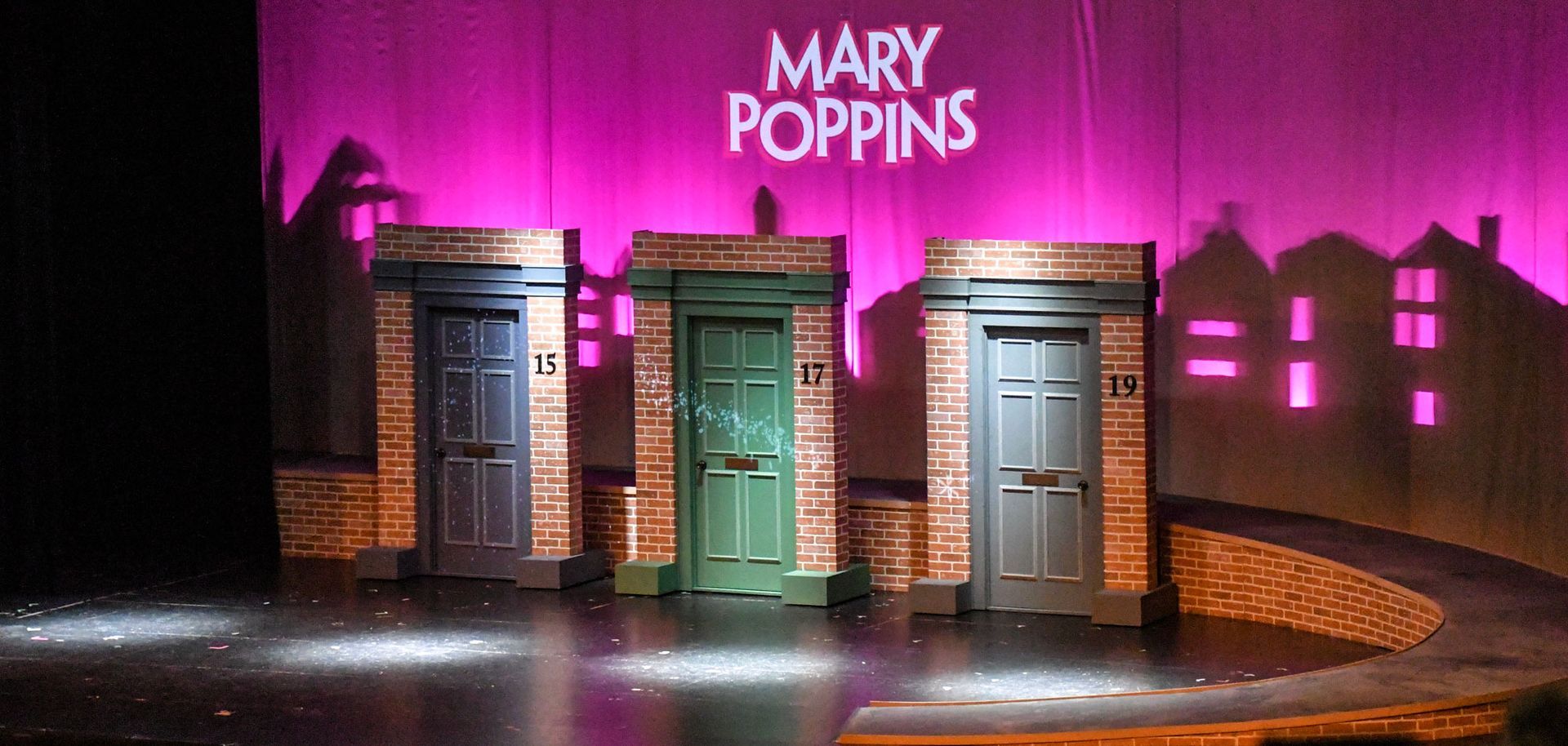 Mary Poppins pre-show stage with three closed house doors, a magenta sky, and the words 
