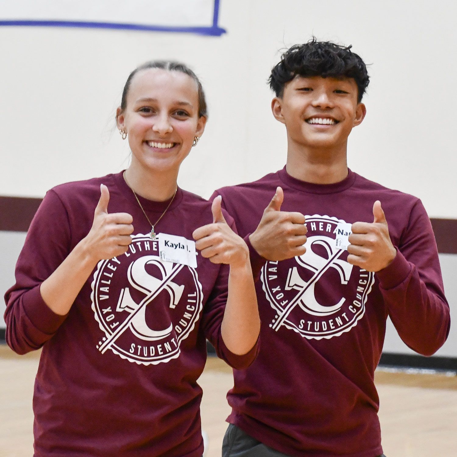 Happy boy and girl students with their thumbs up in the gym