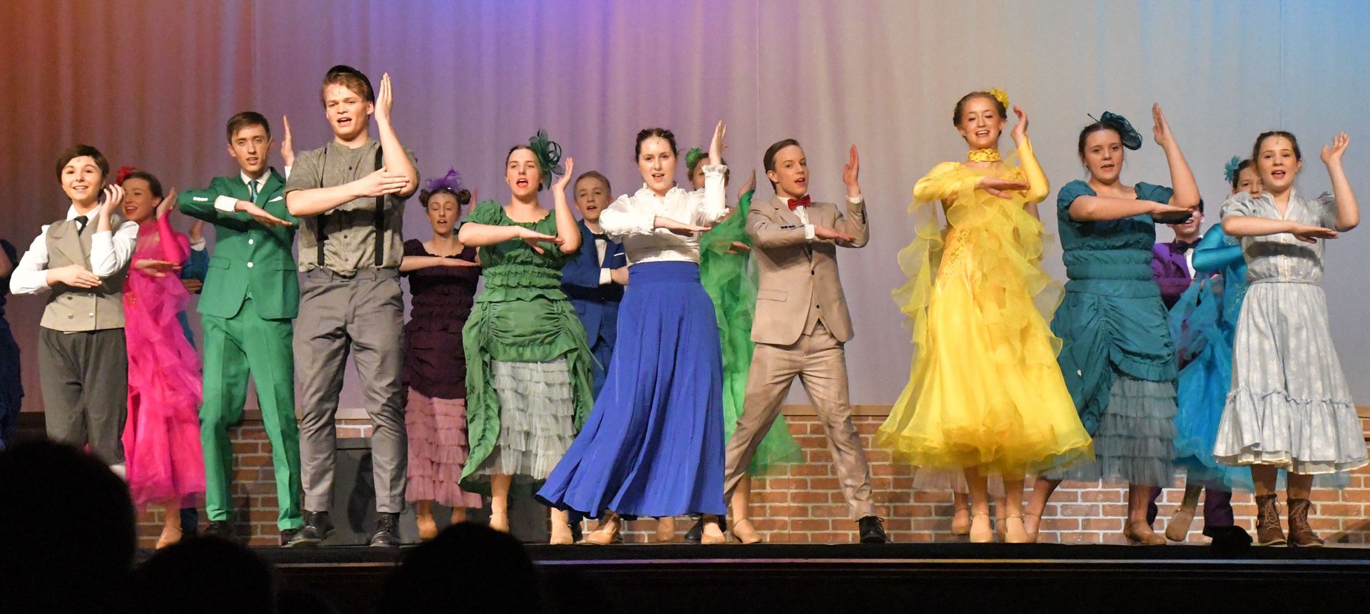 Ensemble dancing with lots of people dress in brightly colored clothes.