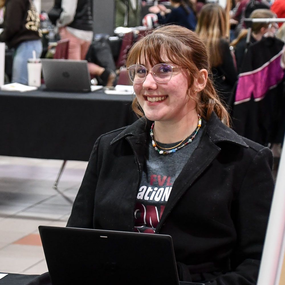 Smiling female student sitting in front of a computer in commons