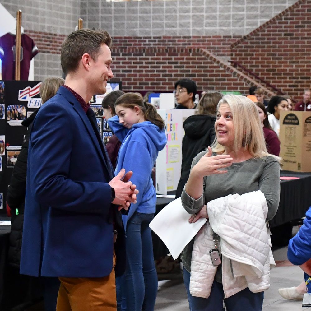 Mr. Blum talking to a female visitor at the Open House event