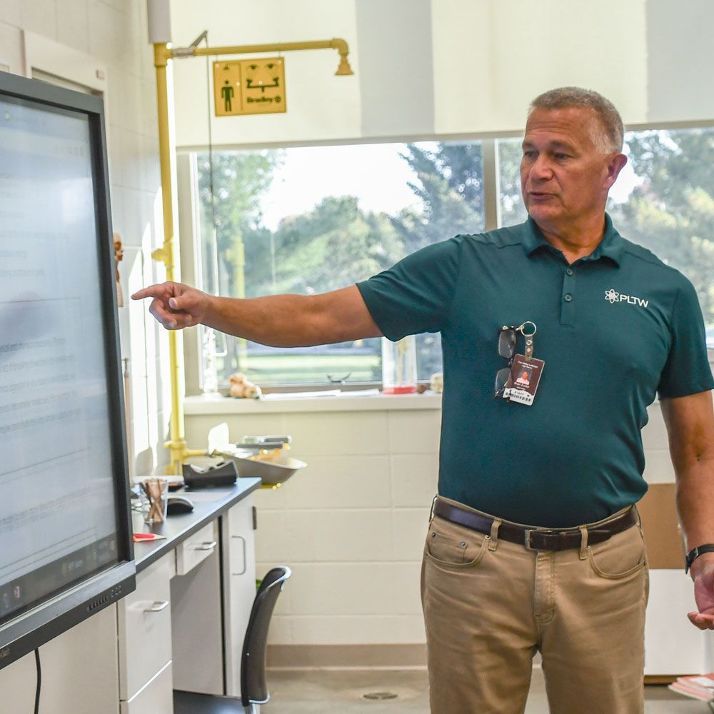 Brian Zunker at the front of his classroom, interacting with a smart board, and teaching