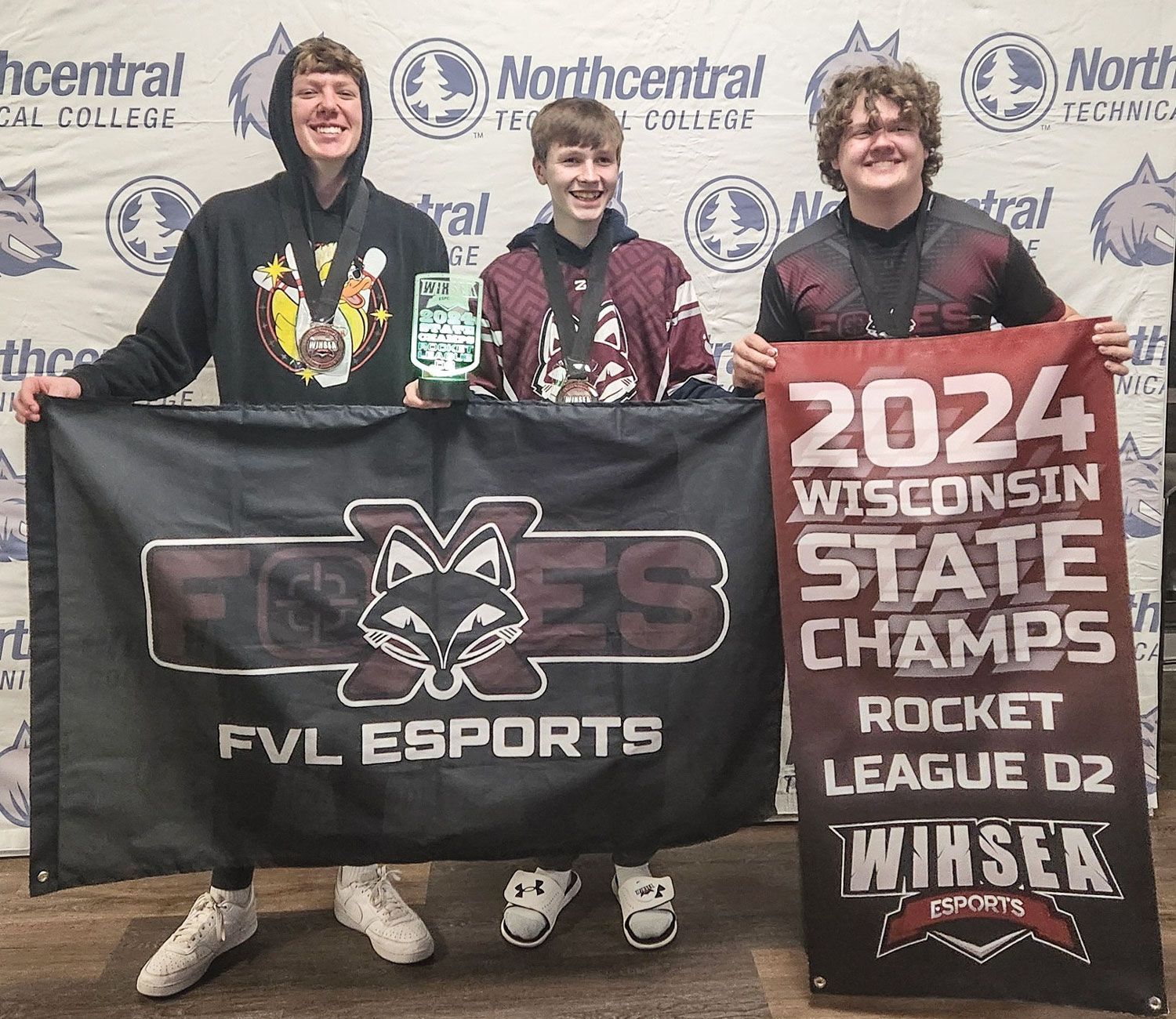Winning team members holding banners - one is for FVL Esports and the other is for the 2024 State Champs.
