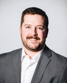 Head shot of smiling Tyler Dorn in white shirt and jacket