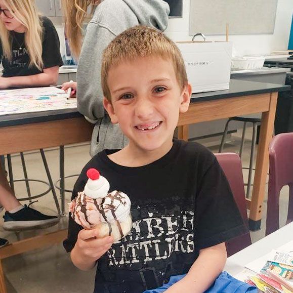 Happy, young, male student holding an art project that looks like an ice cream sundae