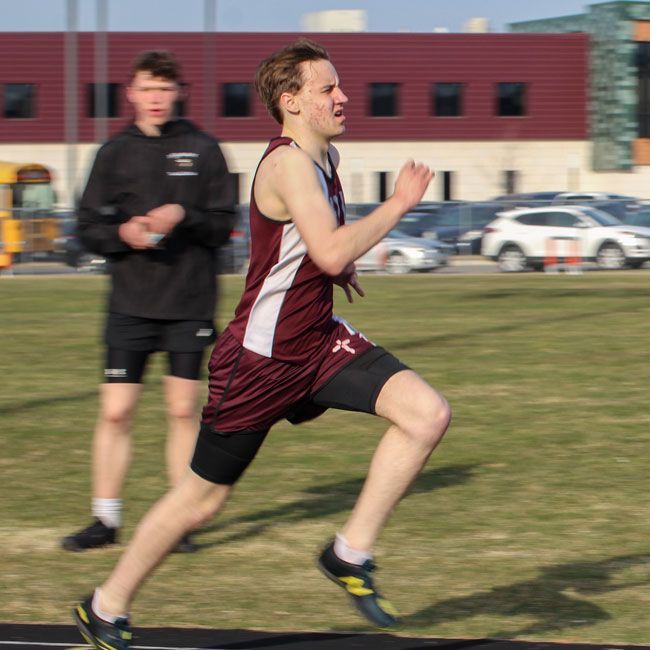 Male track participant running intently during a race