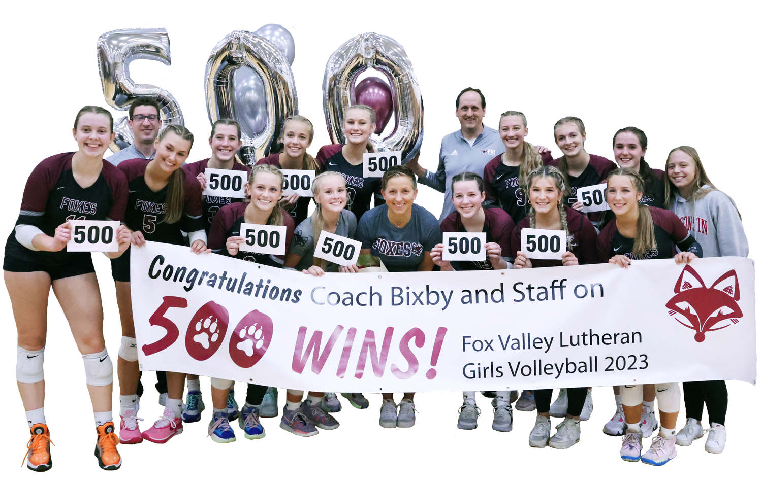 Volleyball team, each holding the number 500, Mrs. Bixby in the middle of the group, a 500 wins banner in the front and balloons in the back