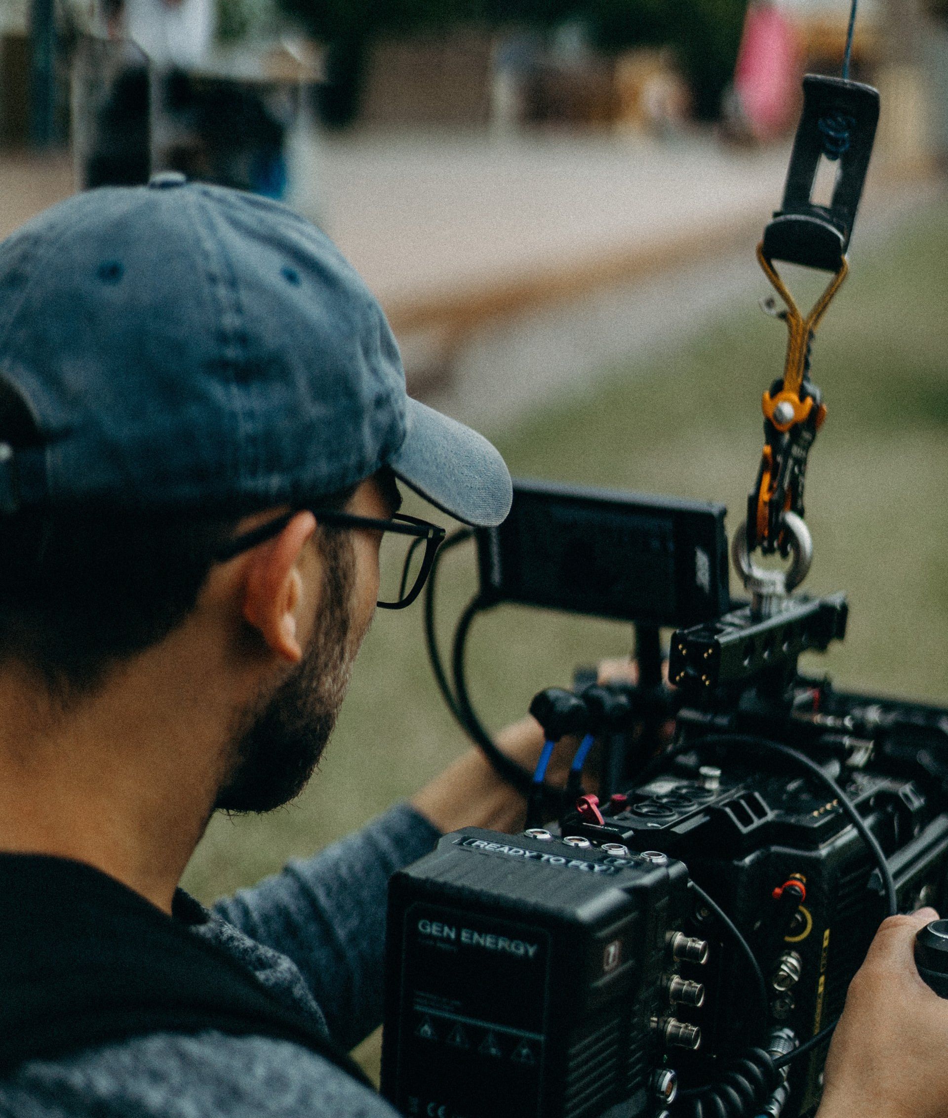 A man wearing a hat and glasses is holding a camera.