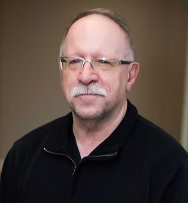 A man with glasses and a mustache is wearing a black shirt.