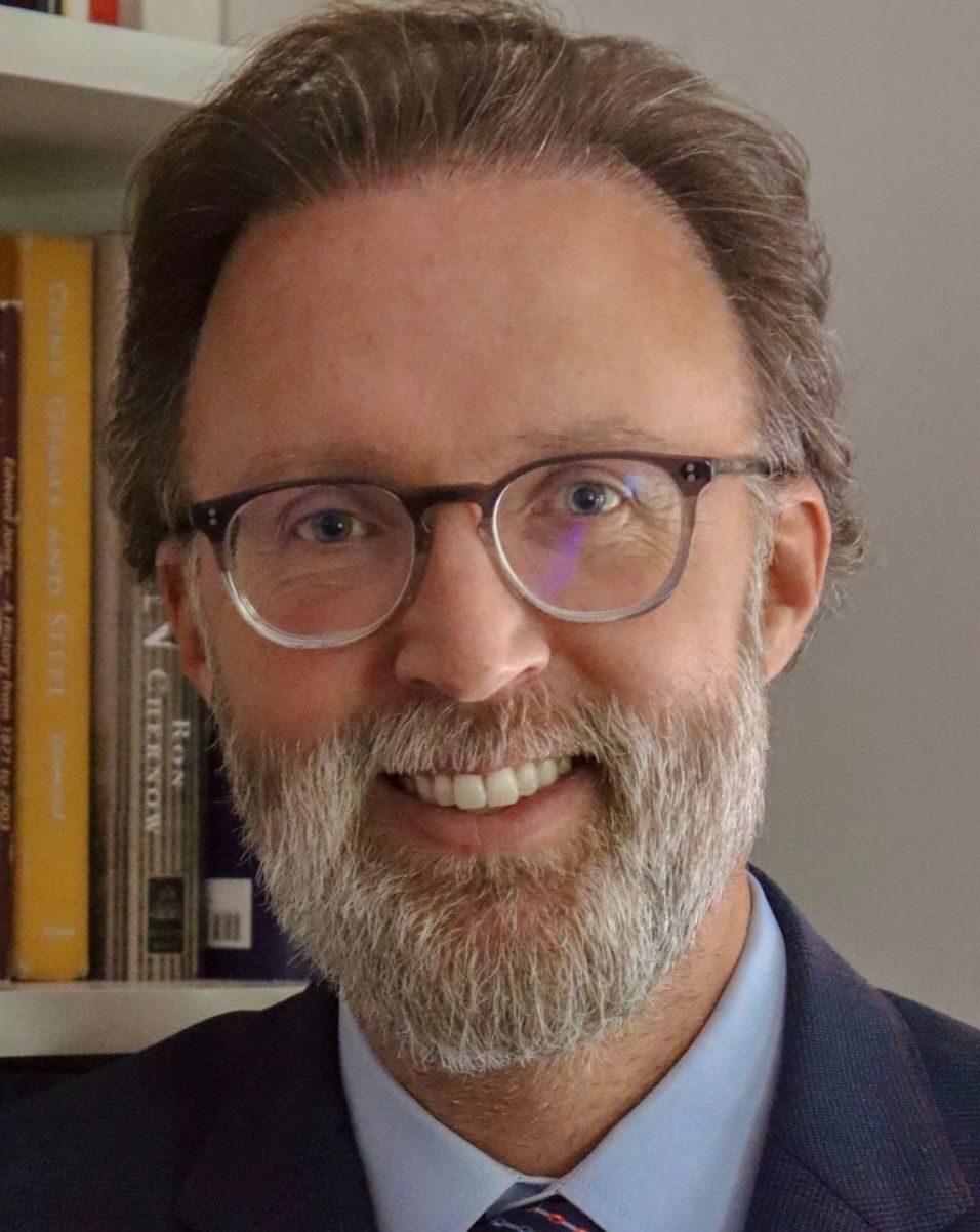 A man with glasses and a beard is smiling for the camera