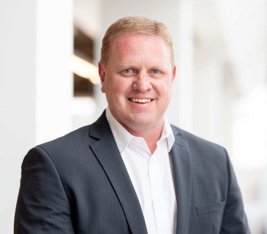 A man in a suit and white shirt is smiling for the camera.
