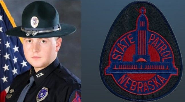 A nebraska state patrol officer stands in front of an american flag