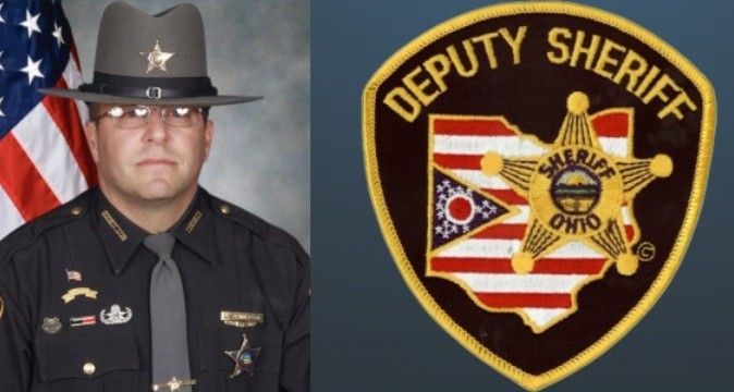 A deputy sheriff is standing in front of an american flag