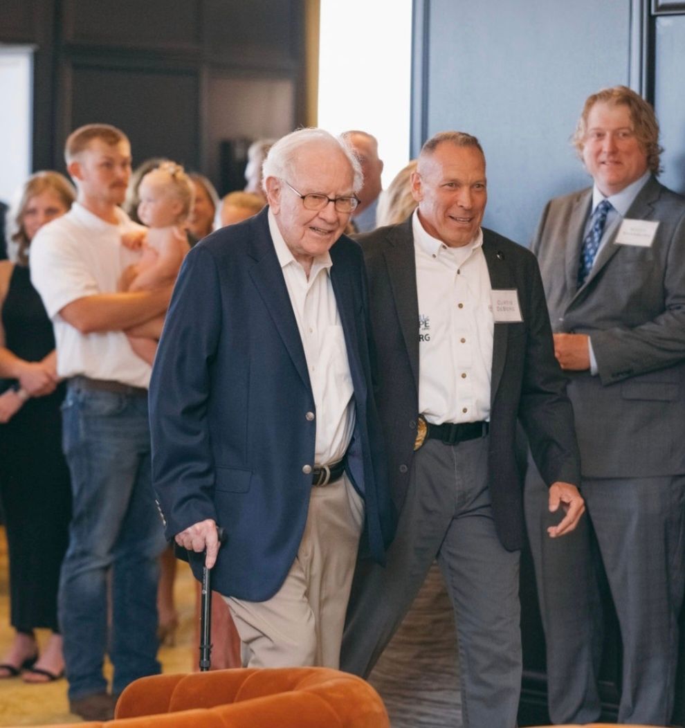 A group of men are standing in a room and one of them is holding a cane