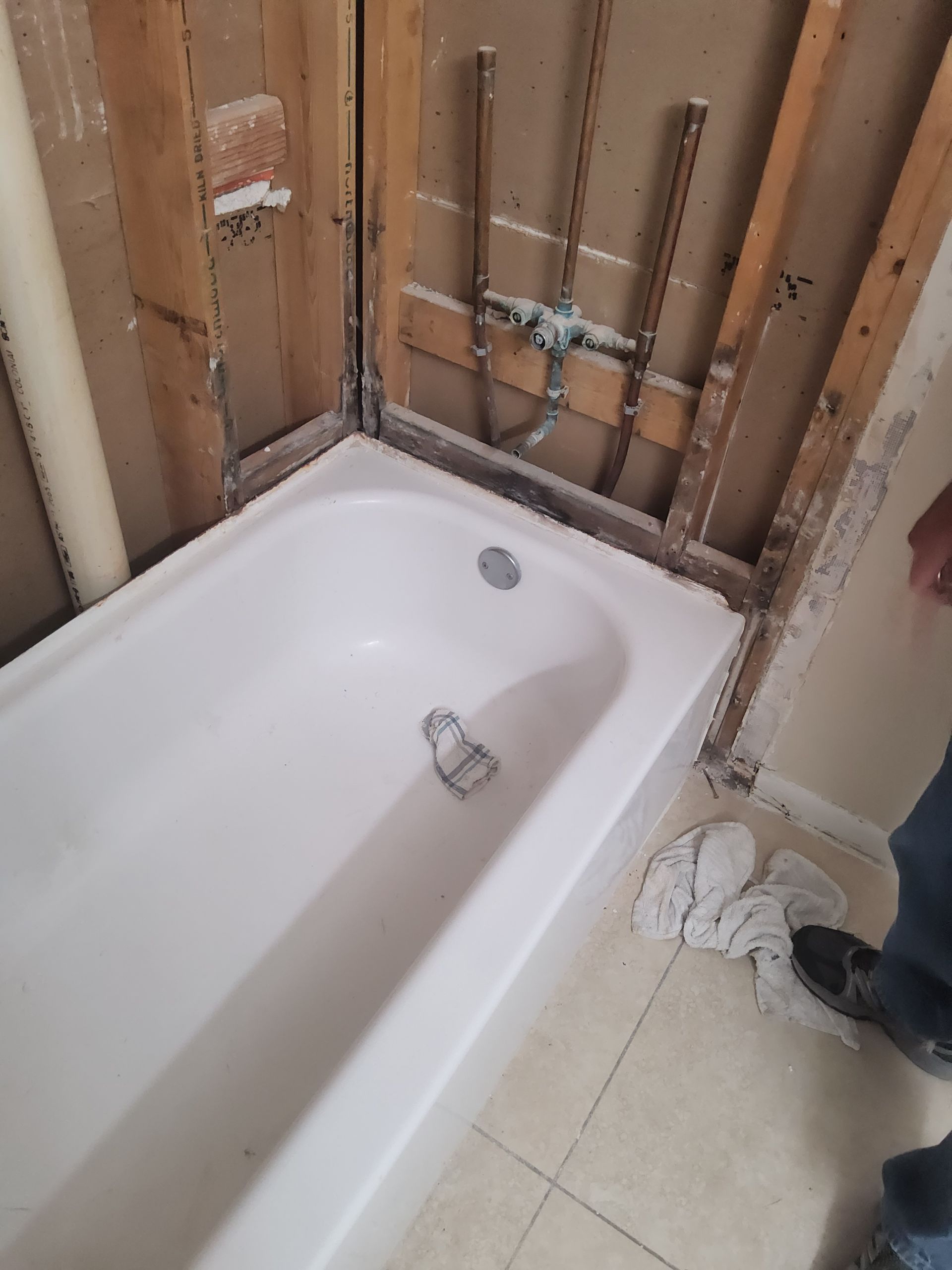 White bathtub installed in a bathroom under construction with exposed wooden studs.