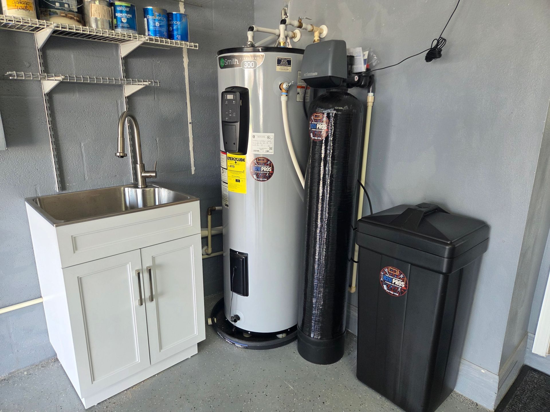 A utility sink, water heater, and water softener in a garage setting.