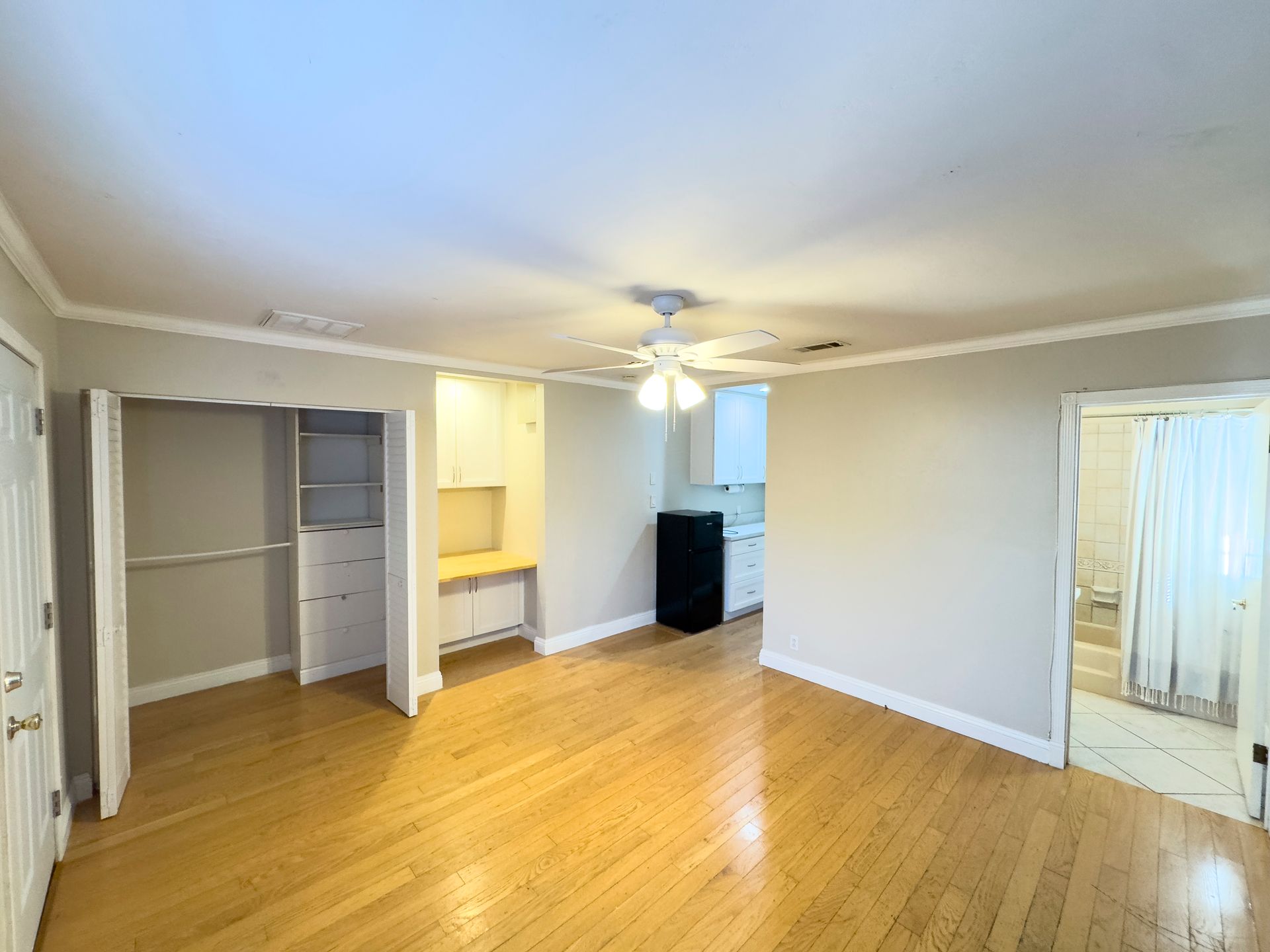 An empty living room with hardwood floors and a ceiling fan.