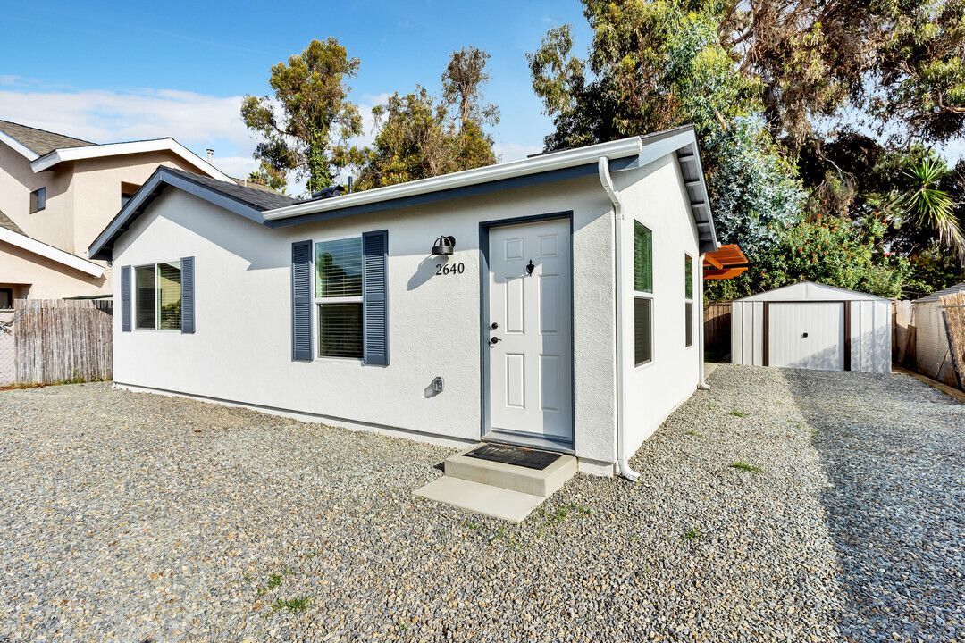 A small white house with a garage in the backyard.