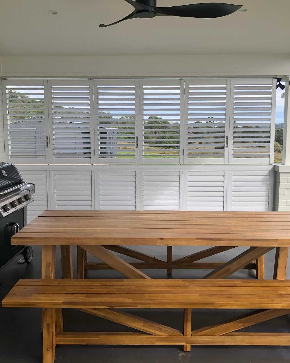 White Shutter Window and Wooden table — Tamworth Blinds & Awnings in Tamworth, NSW
