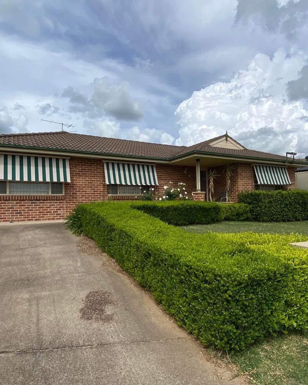 A Brick House With Green and White Awnings on the Windows — Tamworth Blinds & Awnings in Gunnedah, NSW