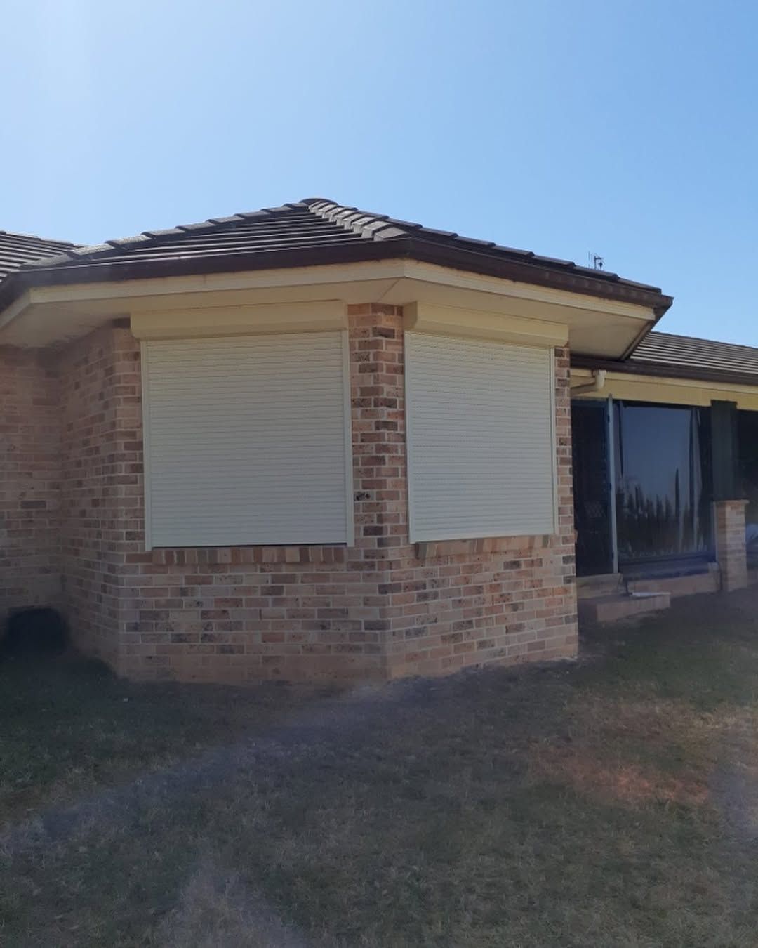 A Brick House With White Roller Shutters on the Windows — Tamworth Blinds & Awnings in Walcha, NSW