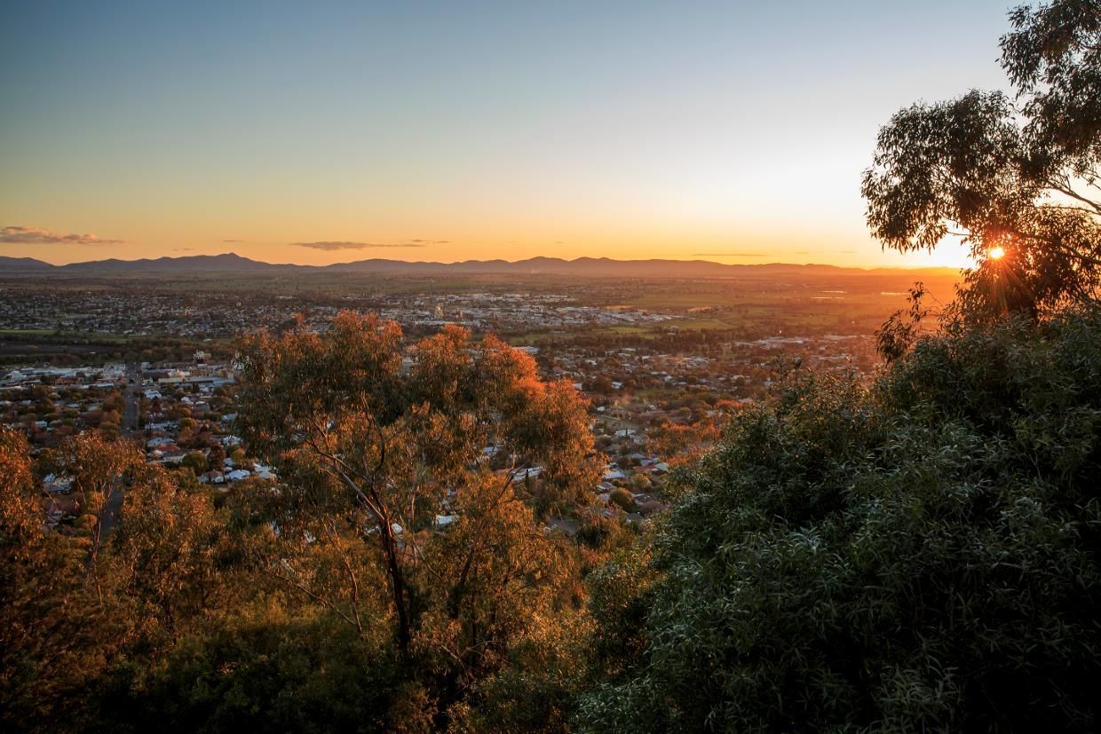 The Sun is Setting Over a City Surrounded by Trees — Tamworth Blinds & Awnings in Tamworth, NSW
