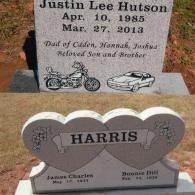 Two gray granite headstones in a cemetery; one with a motorcycle and car, the other heart-shaped with the name Harris.
