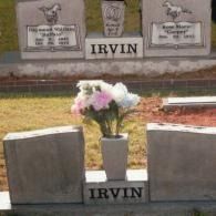 Two gravestones with the surname IRVIN centered below a flower vase in a cemetery setting.