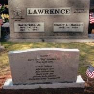 Two headstones in a cemetery, with the name LAWRENCE engraved on the top stone and names of family members below.