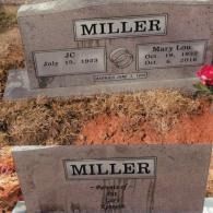 Two stacked headstones for the Miller family, featuring names and dates, set in a graveyard with reddish soil.