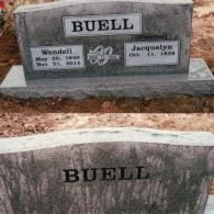 Two gray granite grave markers for the Buell family set in dirt, with dates and a central decorative heart motif.