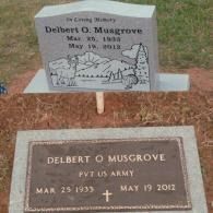 Two grave markers for Delbert O. Musgrove, including an upright gray stone with nature etching and a bronze military plaque.