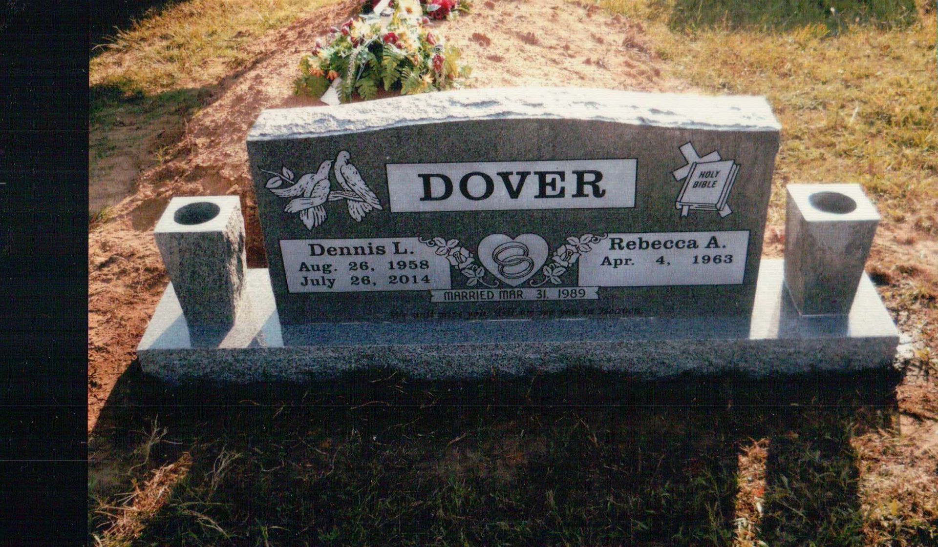 A granite double headstone for the Dover family, featuring two names, dates, and decorative carvings in a cemetery.