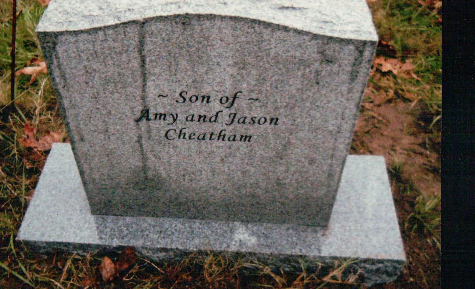 A gray stone headstone in a grassy setting with the engraved text: 