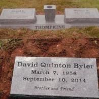 A grey stone grave marker for David Quinton Byler (1956–2014) in front of another family monument labeled 