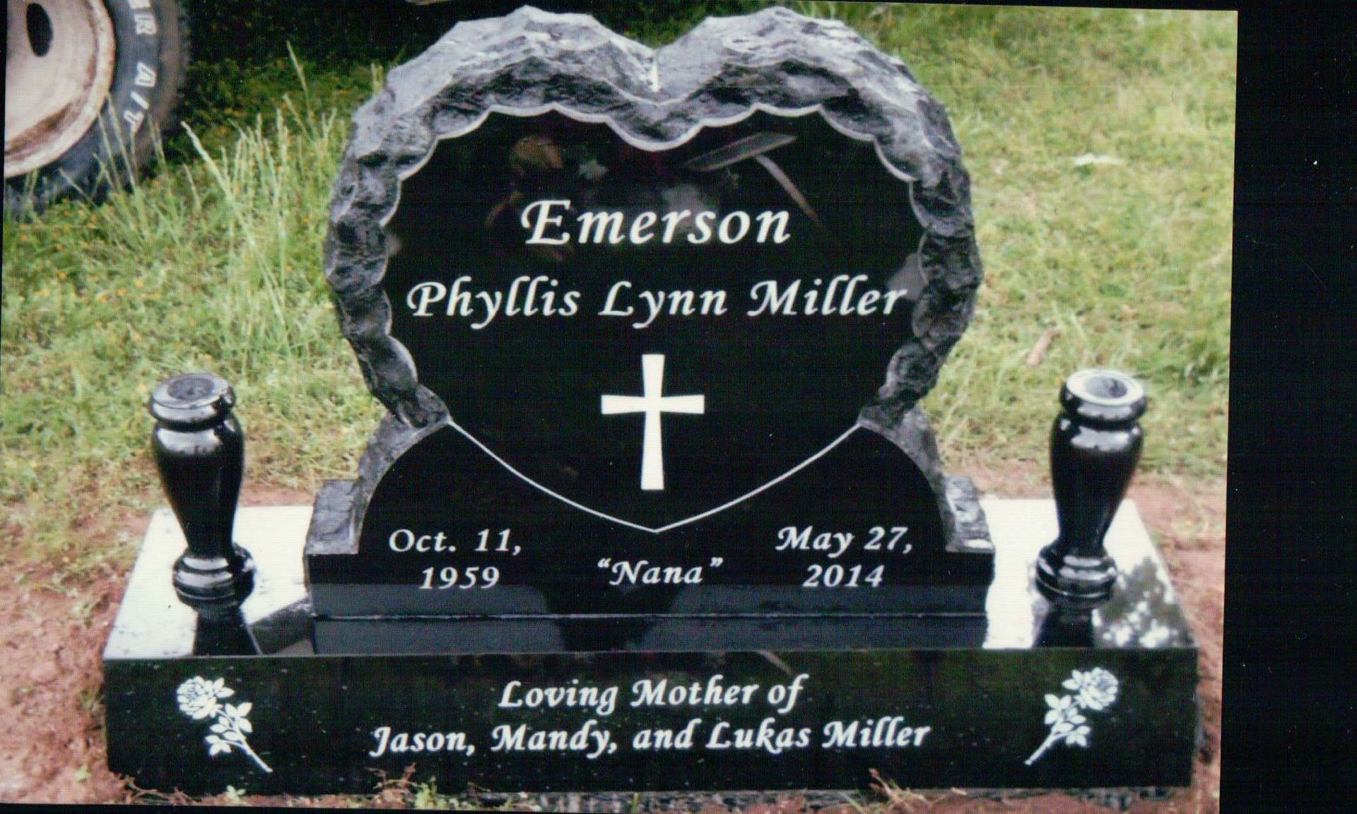 Black, heart-shaped gravestone for Phyllis Lynn Miller with dates 1959–2014, a cross, and an inscription to her children.