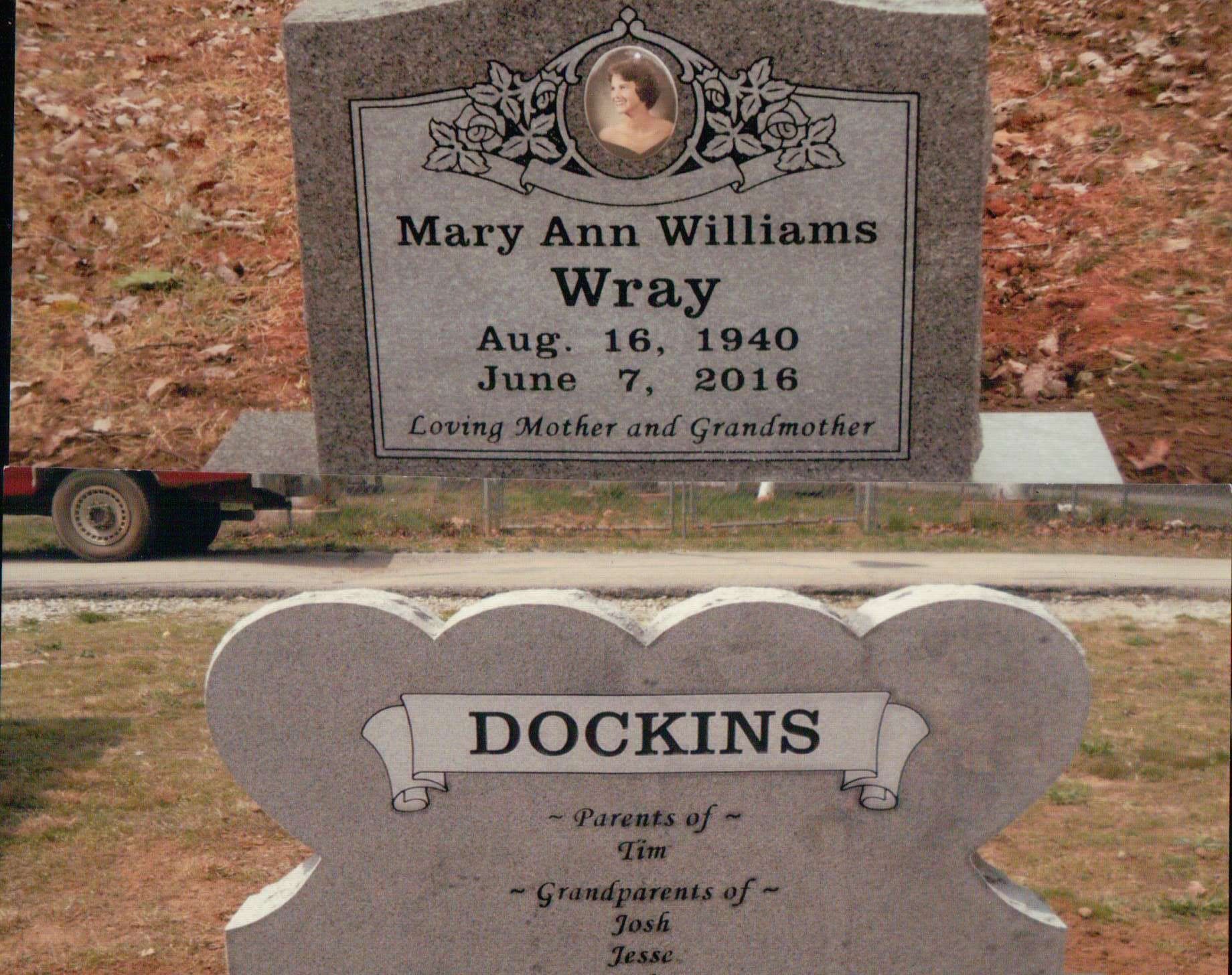 Two gray stone grave markers. The top one reads 