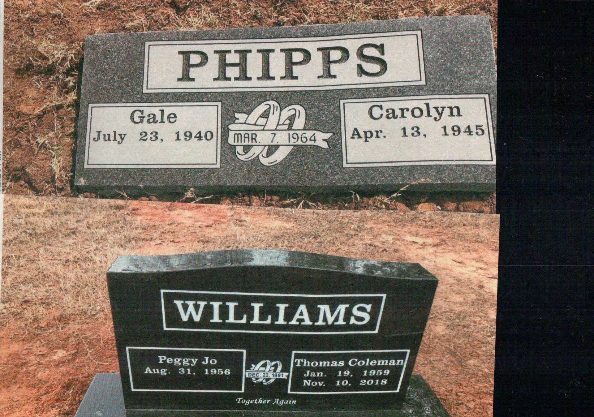 Two grave markers with the family names Phipps and Williams, set on a red-toned, earthen ground.