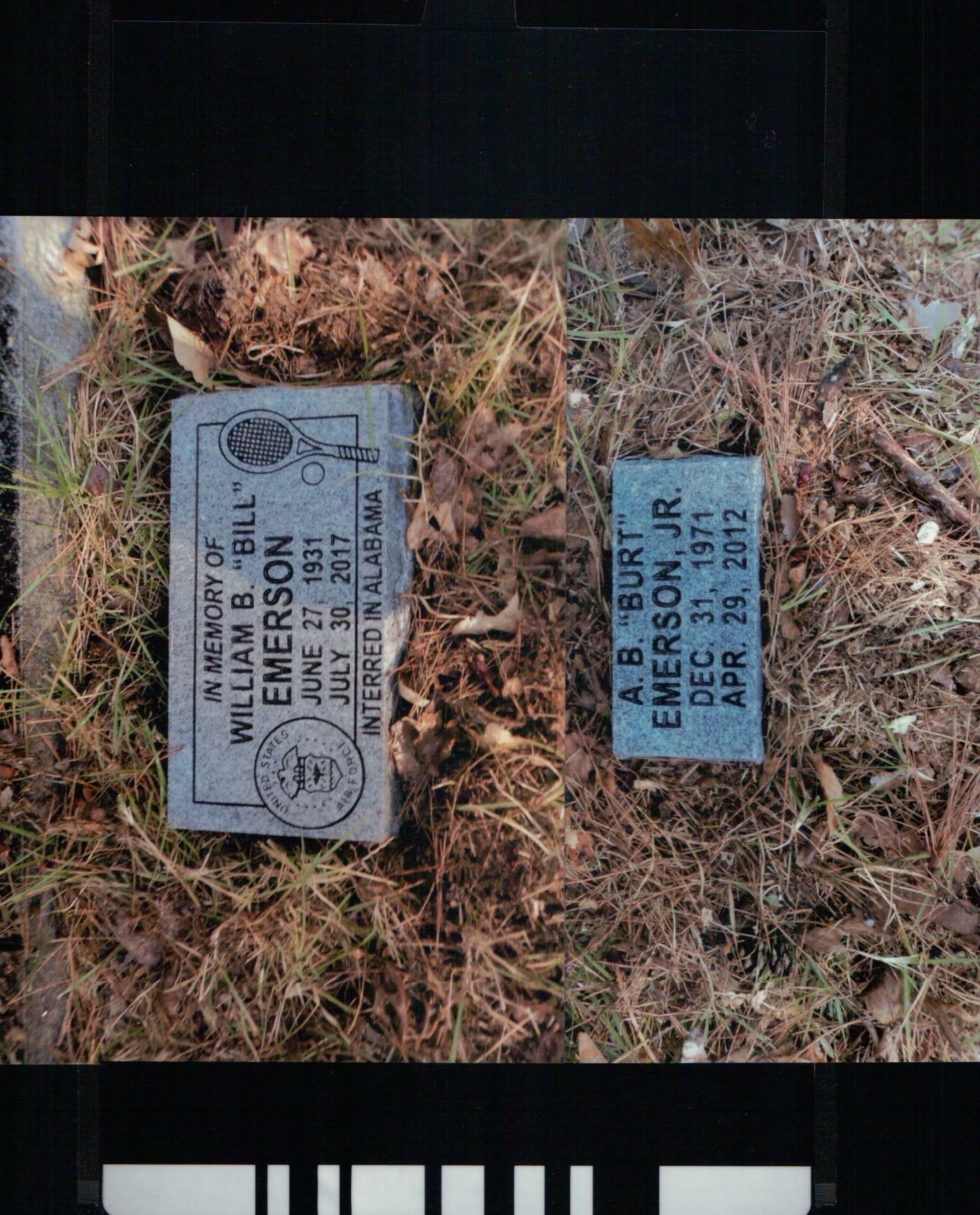 Two rectangular gray grave markers resting on dry grass, inscribed with the names William B. Emerson and A.B. Emerson Jr.