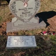 A heart-shaped headstone for Beverly Ann Ratliff and a flat marker for Mary Laverne Murphy in a grass cemetery.