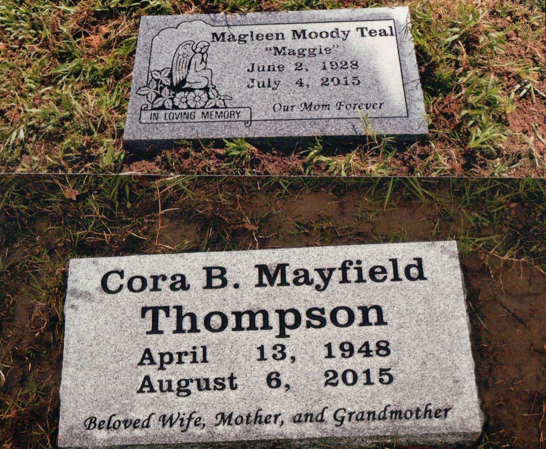 Two rectangular gray granite grave markers set in the grass, displaying names and dates of the deceased.