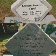 A gray headstone for Lucas Aaron Orf, with birth/death dates and names of his family members inscribed on both sides.