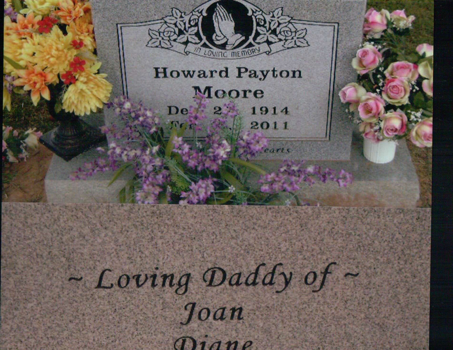 A granite grave marker for Howard Payton Moore, featuring floral arrangements and an inscription listing his children.