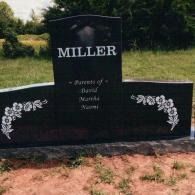 A black granite grave marker reads 