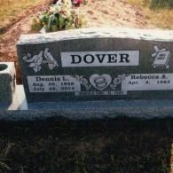 A granite headstone for the Dover family, inscribed with names and dates for Dennis L. and Rebecca A. in a grassy cemetery.