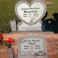 Two gray granite grave markers in a grassy cemetery. The back one is heart-shaped; the front one features a car engraving.