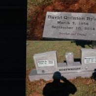 A grave marker for David Quinton Byle above a family headstone with the name Boatwright, with a person's shadow visible.