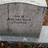 A gray stone grave marker engraved with the words: 
